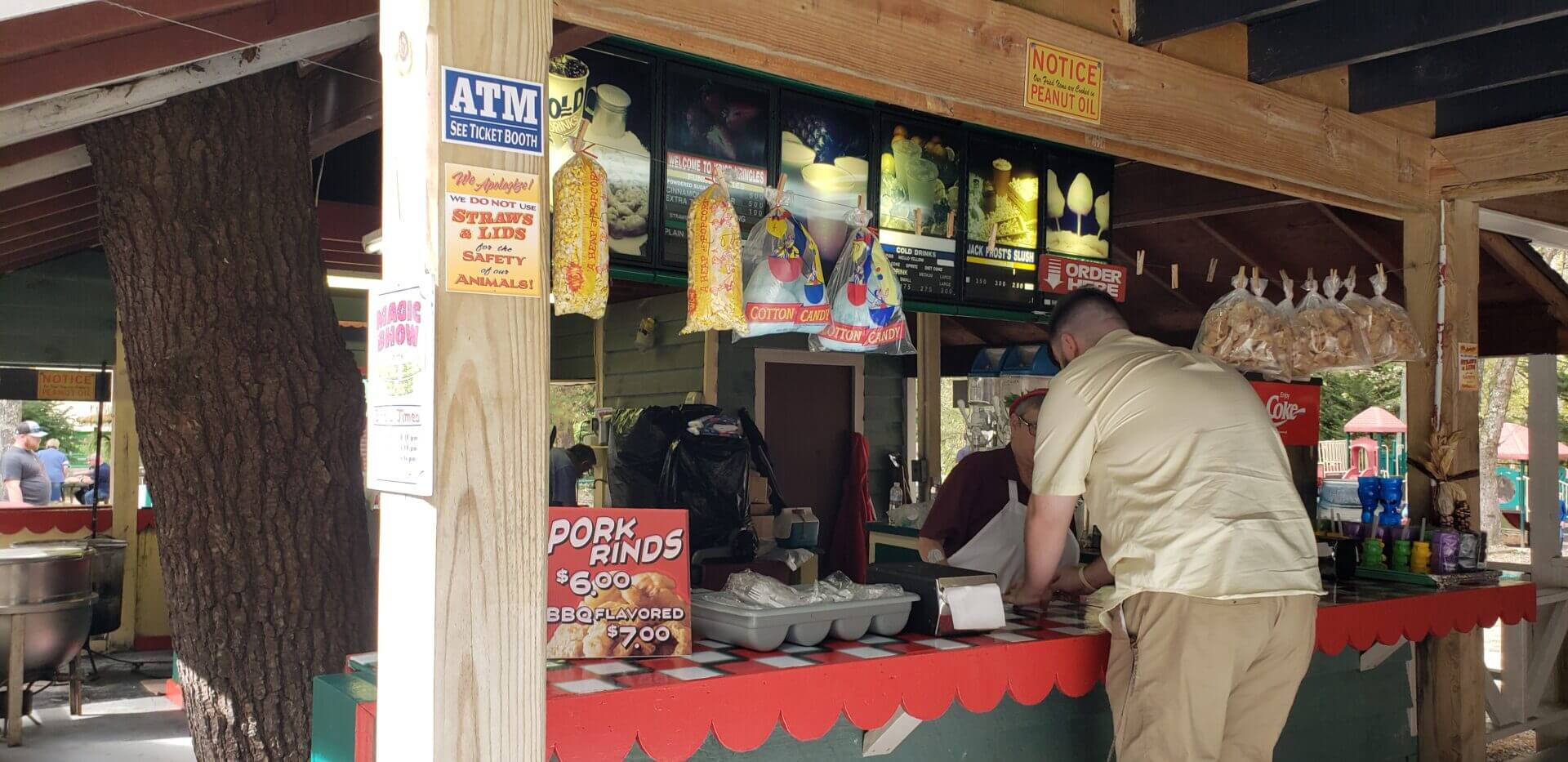 Small food stall selling snacks and drinks with a customer at the counter.